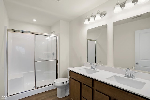 bathroom with toilet, hardwood / wood-style floors, walk in shower, and vanity