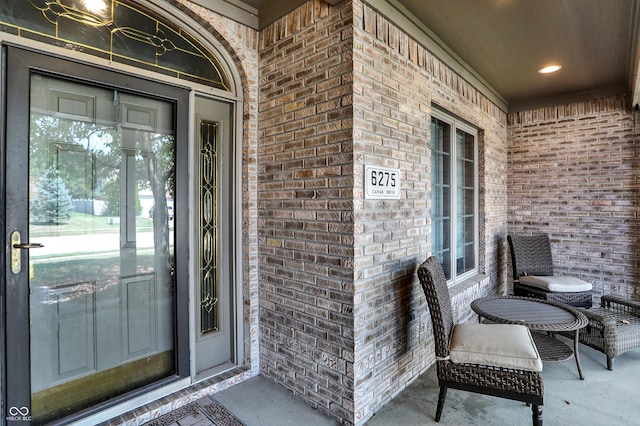 property entrance with covered porch and brick siding