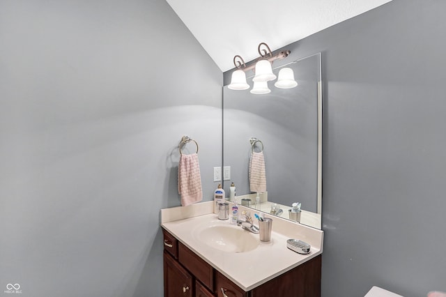 half bathroom featuring vaulted ceiling and vanity