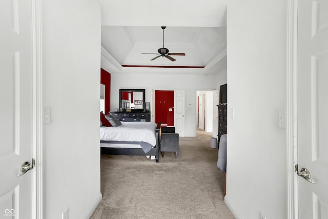 bedroom with a raised ceiling, ceiling fan, ornamental molding, and light carpet