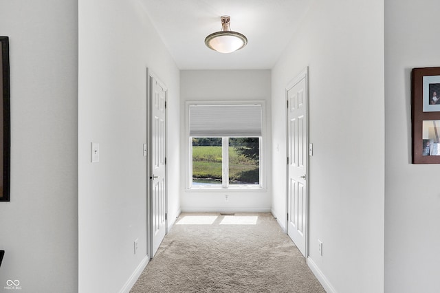 hallway featuring carpet flooring and baseboards