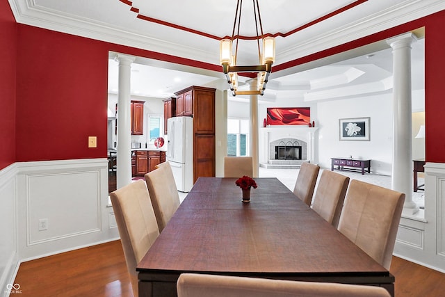 dining area with a notable chandelier, a tray ceiling, decorative columns, dark wood-type flooring, and ornamental molding