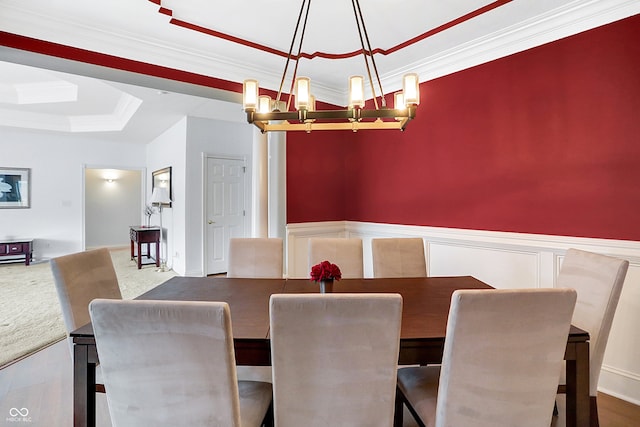 dining space featuring a tray ceiling, hardwood / wood-style flooring, an inviting chandelier, and ornamental molding