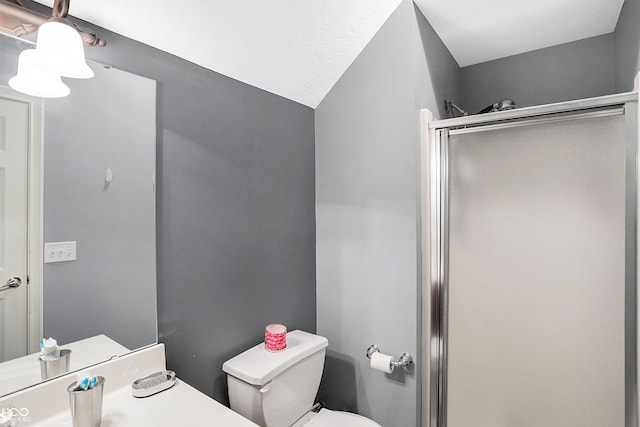 bathroom with vaulted ceiling, toilet, and a shower with shower door