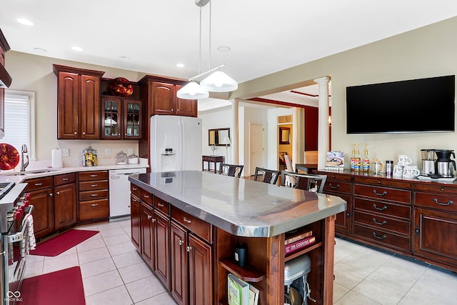 kitchen featuring white appliances, a kitchen breakfast bar, decorative columns, a kitchen island, and hanging light fixtures