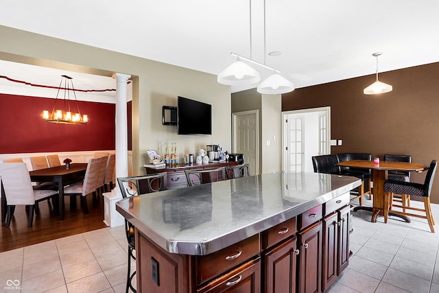 kitchen featuring hanging light fixtures, light hardwood / wood-style flooring, a notable chandelier, ornate columns, and a kitchen island