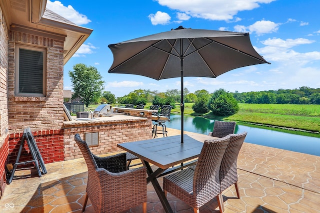 view of patio with a water view, exterior kitchen, and outdoor dining space