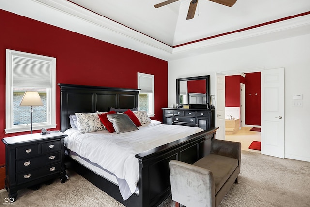 bedroom featuring light carpet, a tray ceiling, connected bathroom, lofted ceiling, and ceiling fan