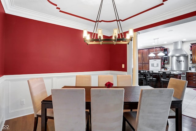 dining space featuring wood-type flooring, an inviting chandelier, and crown molding