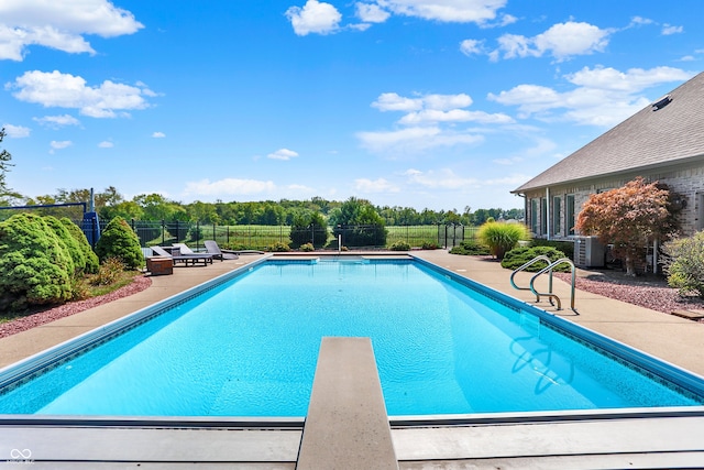 view of swimming pool with a diving board, a patio, fence, and a fenced in pool