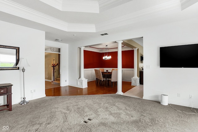 unfurnished living room featuring crown molding, a raised ceiling, a chandelier, and carpet flooring