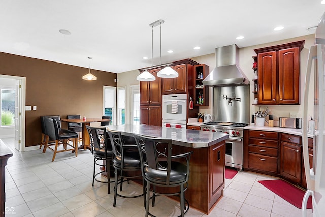 kitchen with a center island, light tile patterned floors, stainless steel stove, double oven, and ventilation hood