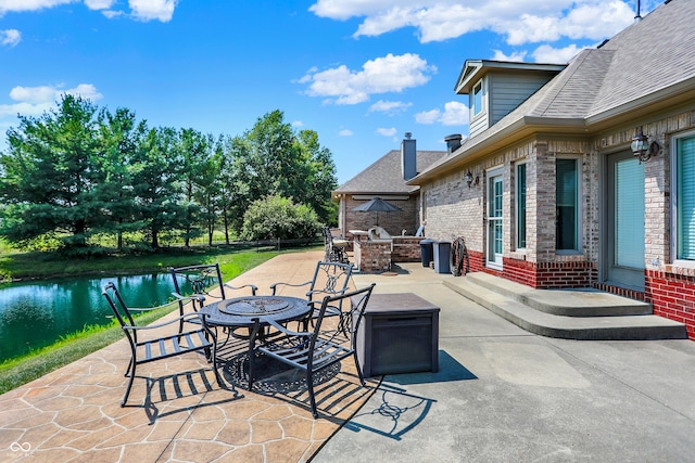 view of patio with outdoor dry bar, exterior kitchen, an outdoor fire pit, and a water view