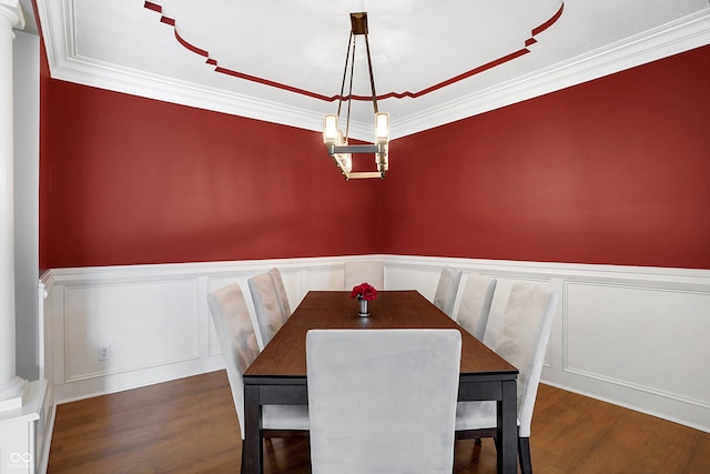 dining area featuring ornate columns, wood finished floors, and wainscoting