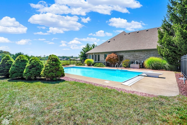 outdoor pool featuring fence, a diving board, a patio, and a yard