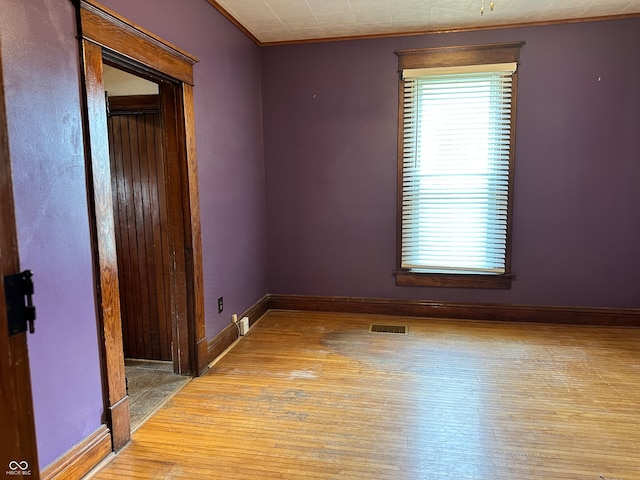 empty room with ornamental molding and hardwood / wood-style flooring