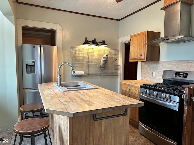 kitchen with appliances with stainless steel finishes, sink, butcher block countertops, wall chimney exhaust hood, and a center island with sink