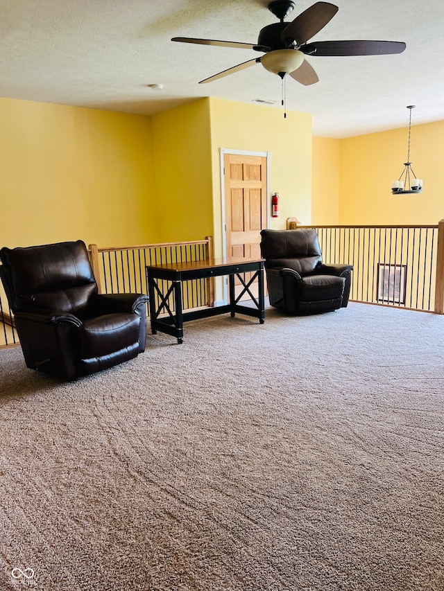 sitting room with a textured ceiling, ceiling fan, and carpet flooring