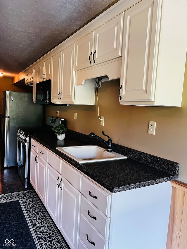 kitchen featuring stainless steel range with electric stovetop, white cabinetry, a textured ceiling, dark tile patterned floors, and sink