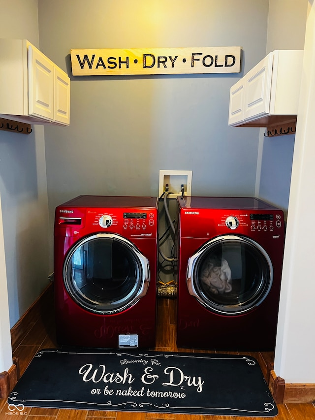 washroom with washer and clothes dryer, hardwood / wood-style floors, and cabinets