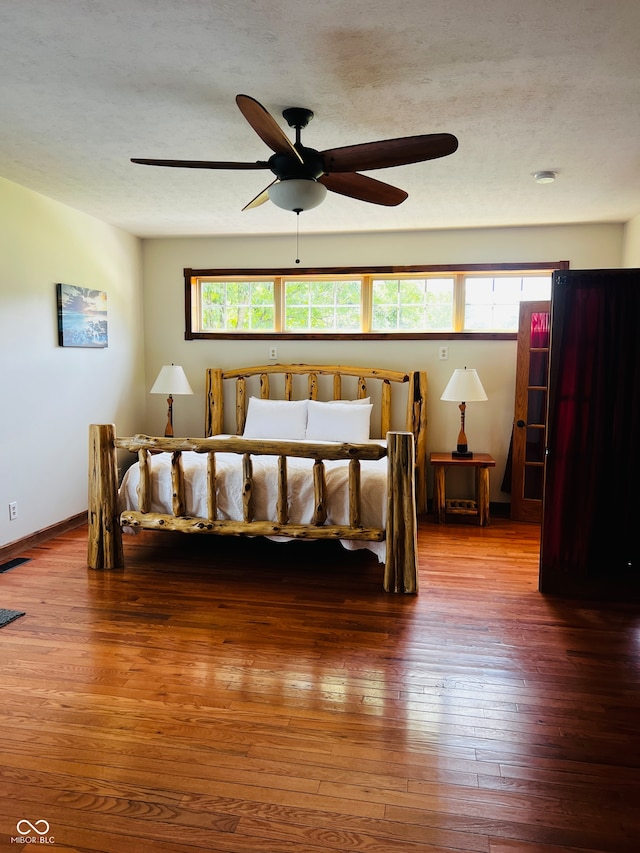 bedroom with multiple windows, ceiling fan, dark hardwood / wood-style floors, and a textured ceiling