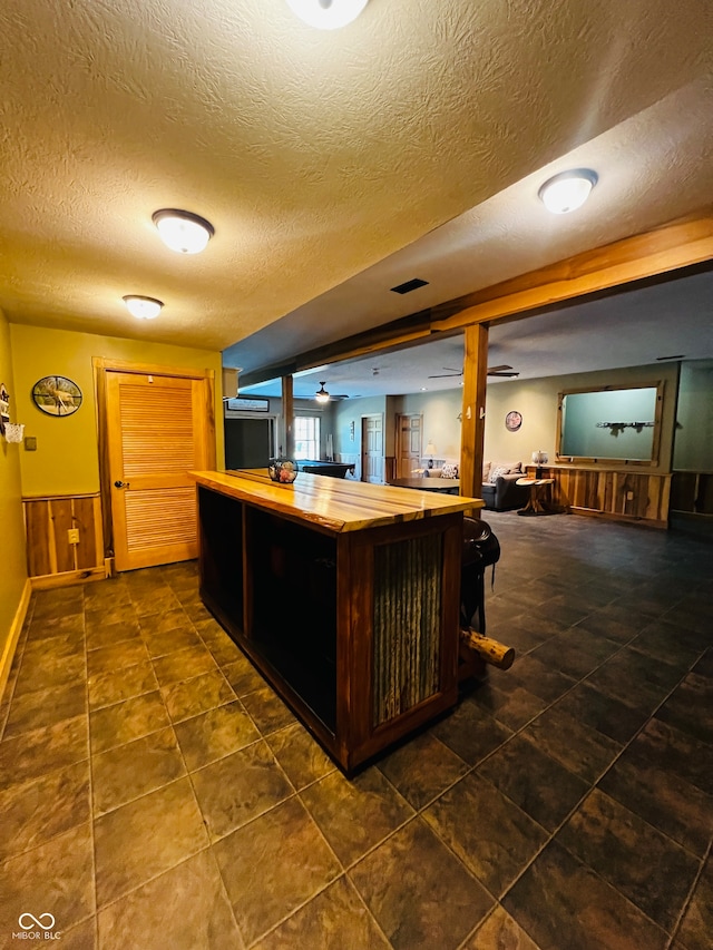 bar featuring dark tile patterned flooring, wood counters, and a textured ceiling