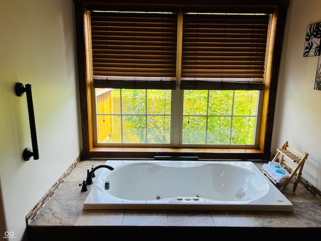 bathroom featuring tiled bath and a healthy amount of sunlight