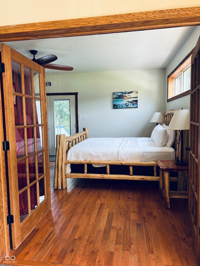 bedroom featuring dark hardwood / wood-style flooring, beamed ceiling, ceiling fan, and multiple windows