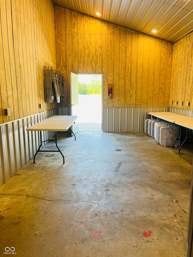 interior space featuring wooden ceiling, vaulted ceiling, wood walls, and concrete flooring