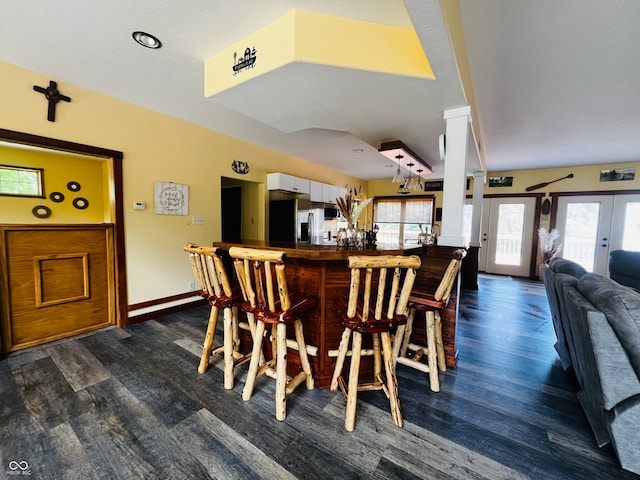 dining area with dark wood-type flooring, indoor bar, and french doors