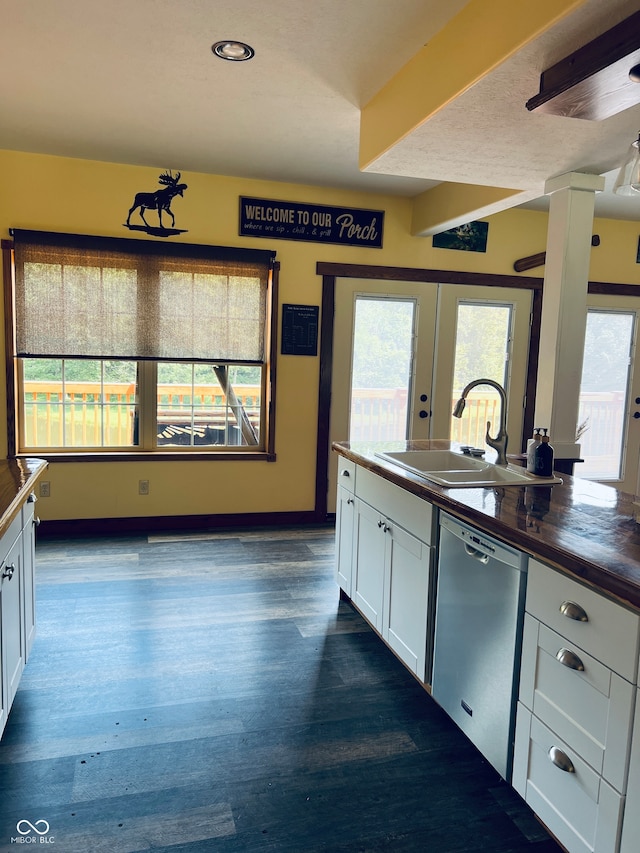 kitchen featuring dark hardwood / wood-style flooring, stainless steel dishwasher, sink, wooden counters, and white cabinets