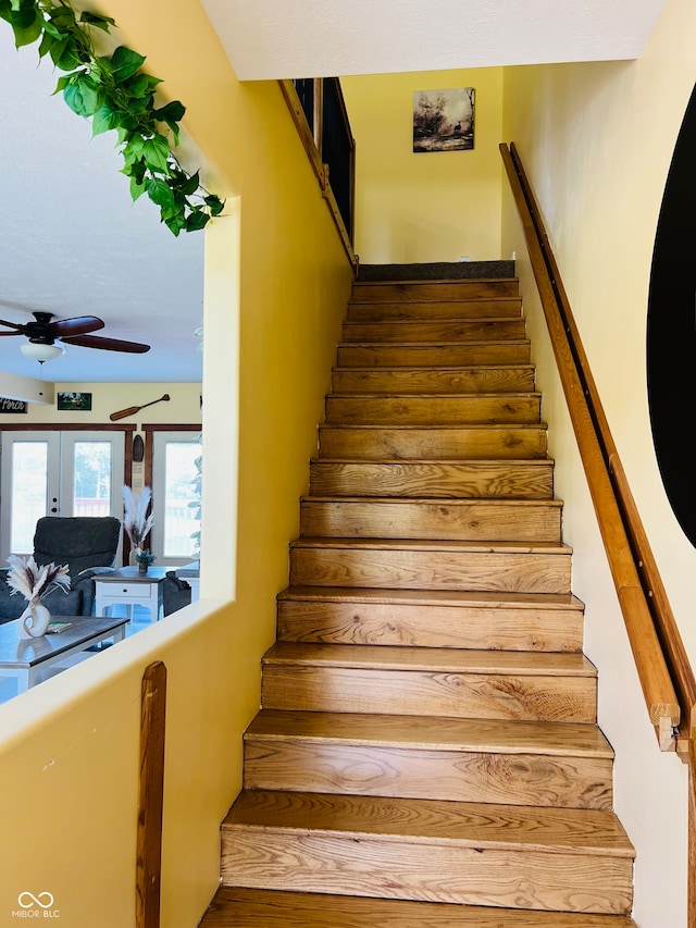 stairs featuring ceiling fan