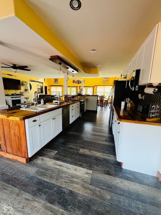 kitchen with white cabinetry, kitchen peninsula, sink, ceiling fan, and black dishwasher