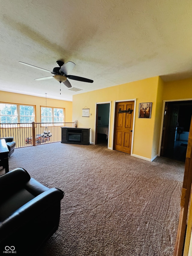 living room featuring a textured ceiling, carpet flooring, and ceiling fan