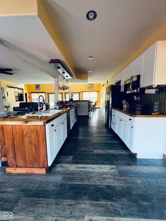 kitchen featuring dark hardwood / wood-style floors, backsplash, kitchen peninsula, sink, and white cabinets