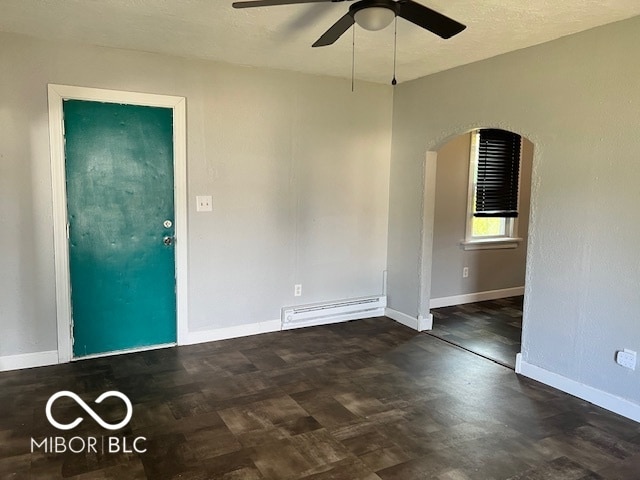 unfurnished room with dark wood-type flooring, a textured ceiling, baseboard heating, and ceiling fan