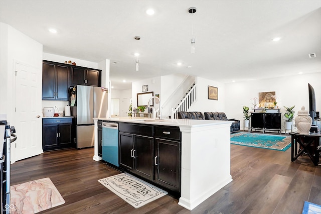 kitchen with appliances with stainless steel finishes, dark hardwood / wood-style flooring, an island with sink, and sink