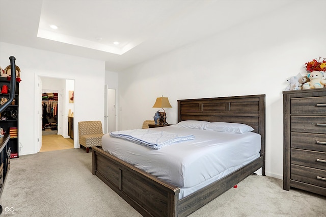 carpeted bedroom featuring a walk in closet, a closet, and a tray ceiling