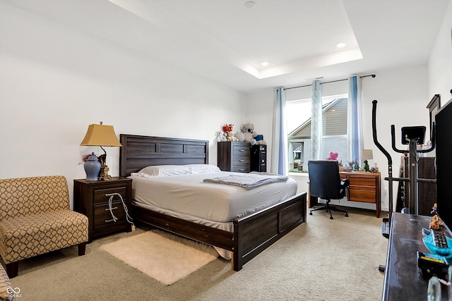 bedroom with a raised ceiling and light colored carpet