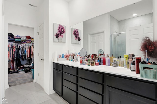 bathroom with a shower with shower door and vanity