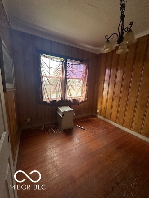 unfurnished room with hardwood / wood-style floors and wooden walls