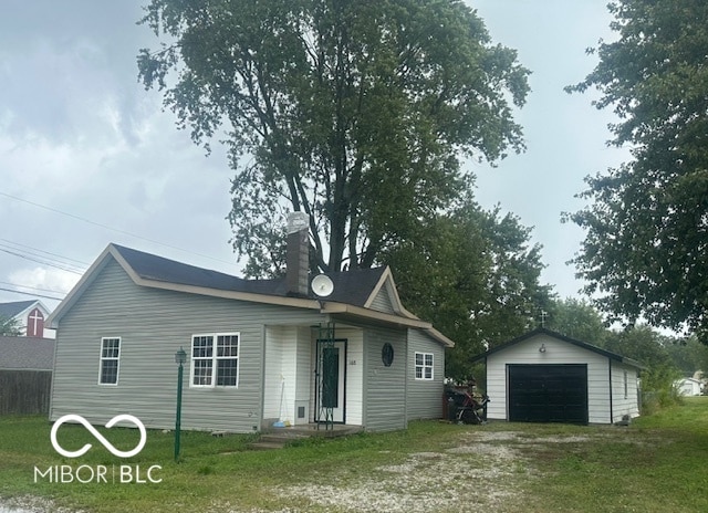 view of front facade featuring a garage, a front lawn, and an outbuilding