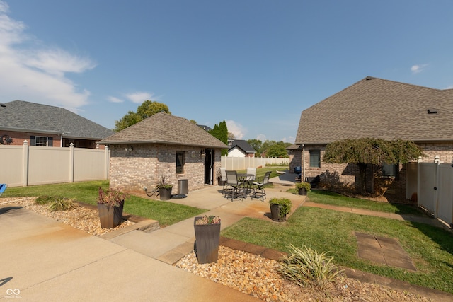 rear view of property featuring a patio, brick siding, an outdoor structure, and a fenced backyard