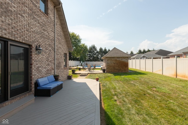 deck with an outbuilding, a lawn, a patio area, and a fenced backyard