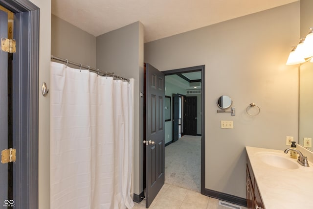 full bath with a shower with shower curtain, tile patterned flooring, baseboards, and vanity