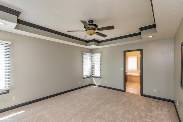 unfurnished bedroom featuring crown molding, carpet, a raised ceiling, and baseboards