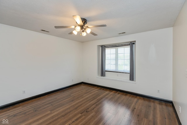 spare room with dark wood-type flooring, visible vents, ceiling fan, and a textured ceiling