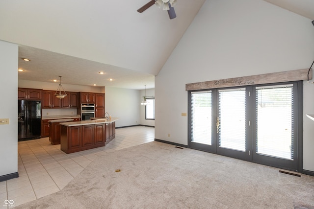 kitchen featuring light countertops, black refrigerator with ice dispenser, an island with sink, and light colored carpet