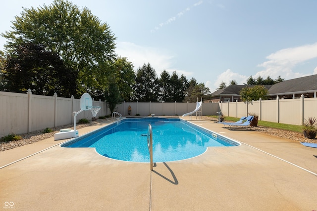 view of swimming pool with a fenced in pool, a water slide, a patio area, and a fenced backyard