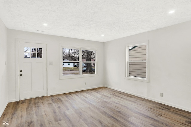 foyer entrance with light hardwood / wood-style flooring and a textured ceiling